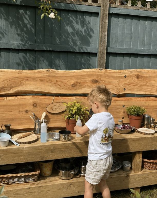 A young child playing at the wooden mud kitchen